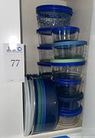 Cabinet view showing stack of glass bowls with lids and metal striped bowl; provides overview and count