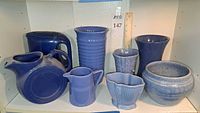 All eight blue ceramic pieces lined on shelf