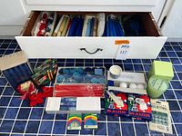 Drawer of assorted loose taper candles and packaged candles displayed on floor