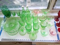 Full lot overview showing quantity and variety of green and pink pressed glass items