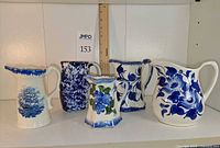 Front view of five ceramic pitchers showing designs and shapes