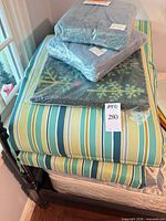 Stacked striped chaise cushions with packaged blue cushion covers and packaged doormat