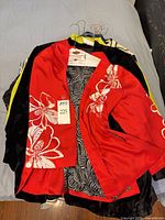 Stack of garments topped by red floral jacket
