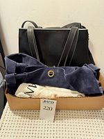 All four handbags stacked in tray with dust bag