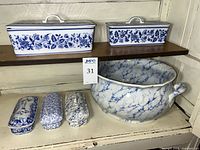 Shelf displaying two lidded containers, three toiletry boxes and footbath