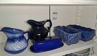 Entire lot on shelf showing both pitchers, butter dish and two planters