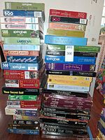 Full view of two tall stacks of boxed puzzles showing quantity and brands