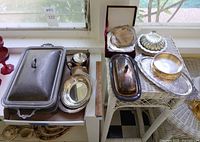 overall view showing multiple silverplate serving pieces on two tables