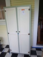 Full frontal view of pastel green and cream Oxford cupboard standing on checkered floor