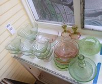 Overview of all pink and green pressed glass pieces on table