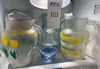 Three pitchers and carafe on shelf