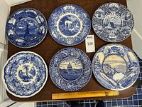 All six blue & white decorative plates arranged on table with ruler for scale