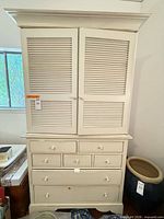 Front view showing louvered doors, seven drawers, distressed white finish