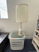 White wicker table with glass top and ceramic lamp displayed together