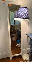 Front view of mirror and powered-on decorative floor lamp