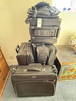 Stacked view of all five black luggage pieces, showing size variety and wheel configurations
