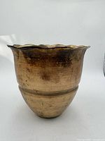 Front view of gold-tone metal planter showing scalloped rim and patina