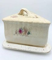 Front view of triangular ceramic cheese dish with lid showing floral decals and crazing