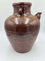 Front view of brown glazed crackle-finish oil jug with side spout and lug handle