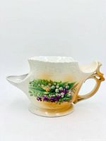 Right side view showing handle, spout, floral motif