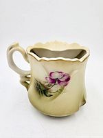 Front view showing floral design and handle of scuttle mug