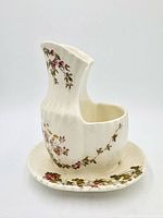 side view of shaving scuttle mug on saucer showing floral transfers