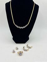 Full view of necklace on stand with ring and earrings displayed