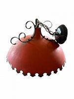 Side view of red metal lamp shade with black scroll hanger and canopy