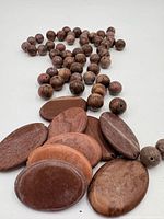 Group of round brown gemstone beads and flat oval gemstone beads on white surface
