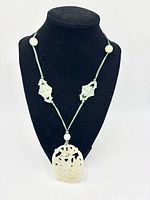 Full necklace on display form showing pendant, carved panels, beads and cord