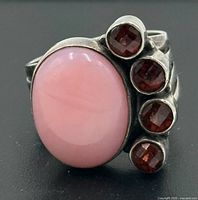Front view showing pink opal cabochon and four red accent stones