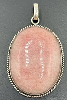 Front view oval pink rhodochrosite cabochon pendant in silver bezel