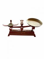Full view of red cast iron balance scale with both pans attached
