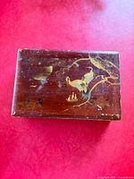 Closed box top showing painted crane motif and surface wear