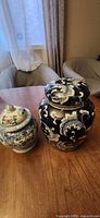 Two porcelain ginger jars side by side on table showing size difference and lid details
