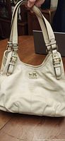 Front view of Coach ivory leather shoulder bag showing overall design and straps