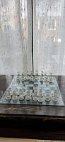 Full view of glass chess set on board showing both clear and frosted pieces