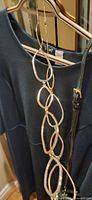 Dress, handbag strap, and gold link necklace hanging on hanger