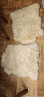 Two small cream sheepskin/faux fur rugs pile side up on parquet floor
