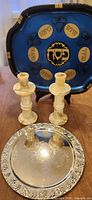 Three-piece Judaica set: seder plate on stand behind onyx candlesticks and silver tray