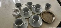 Group showing 6 cups, 6 saucers, 6 metal coasters
