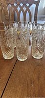 front view of six cut glass tumblers on wooden table