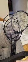 Four black Slazenger badminton rackets stacked together, showing frames and strings
