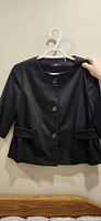 Front view of black Tahari blazer on hanger showing buttons, sleeves, pockets
