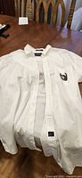 Front view of white Arrow long-sleeve shirt showing buttons, pocket, embroidery