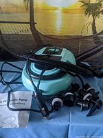 Pump with hose, car plug, six adapters and manual on table