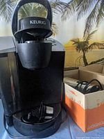 Keurig coffee maker front view with reusable K-cup filter and boxed milk frother