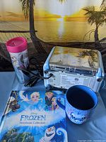 Group shot of toaster rear view, Frozen tumbler, Frozen storybook and Stitch mug against sunset backdrop