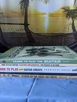 Stack of four guitar instruction/songbooks showing spines and titles