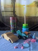 Group shot showing wooden car, dinosaur pull toy, stacking rings, heart bead necklace and Stephen Joseph puzzle tin